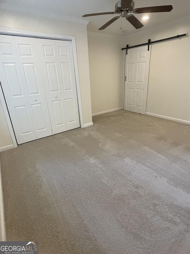 1833 Phillips Ave, East Point, GA 30344 - unfurnished bedroom with a barn door, crown molding, carpet floors, a closet, and a ceiling fan
