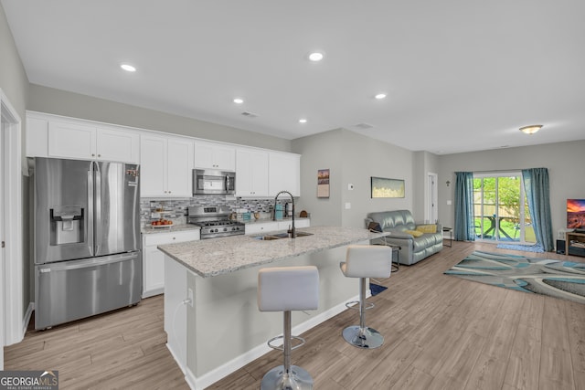 264 Golden Eagle Pkwy, Braselton, GA 30517 - kitchen featuring stainless steel appliances, open floor plan, light wood-style flooring, white cabinetry, and tasteful backsplash