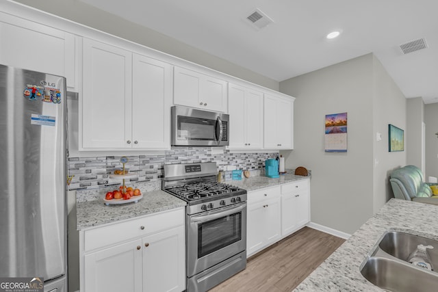 264 Golden Eagle Pkwy, Braselton, GA 30517 - kitchen featuring appliances with stainless steel finishes, decorative backsplash, light wood finished floors, white cabinets, and recessed lighting
