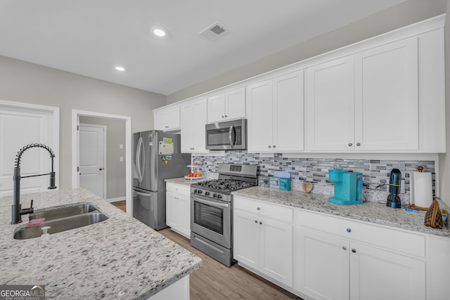 264 Golden Eagle Pkwy, Braselton, GA 30517 - kitchen with appliances with stainless steel finishes, white cabinetry, decorative backsplash, light wood-style flooring, and recessed lighting