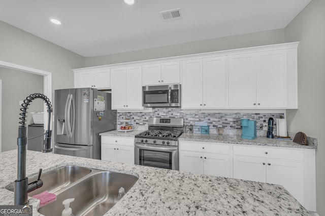 264 Golden Eagle Pkwy, Braselton, GA 30517 - kitchen with appliances with stainless steel finishes, white cabinetry, backsplash, and light stone counters