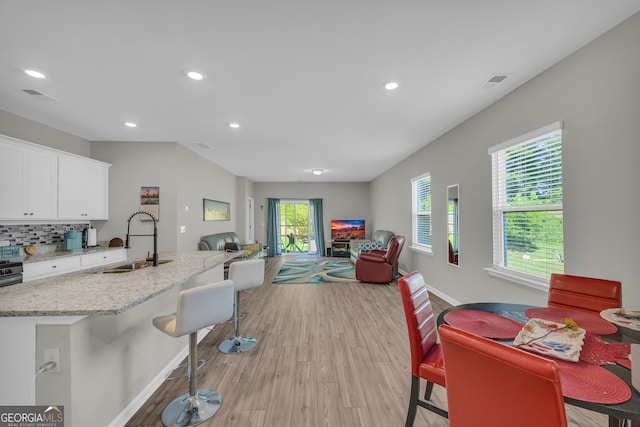 264 Golden Eagle Pkwy, Braselton, GA 30517 - kitchen featuring open floor plan, white cabinets, recessed lighting, light wood finished floors, and light stone counters