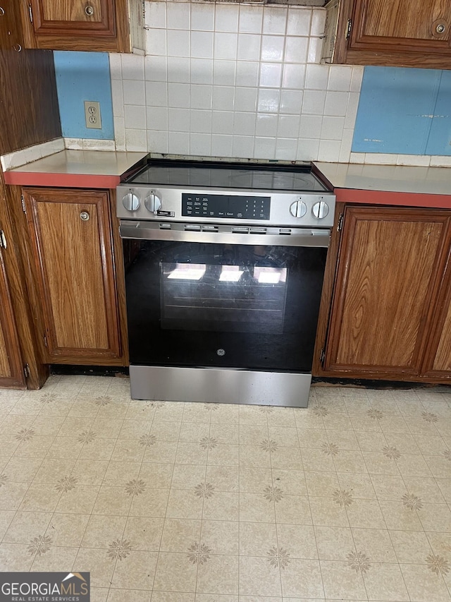 818 Arch Tanner Rd, Bethlehem, GA 30620 - kitchen with stainless steel electric stove, decorative backsplash, and brown cabinetry