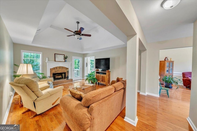 536 Sam Brown Blvd, Commerce, GA 30529 - living room featuring a ceiling fan, a raised ceiling, light wood finished floors, and a brick fireplace