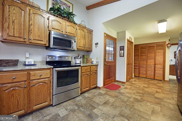 77 Chestatee Dr, Blairsville, GA 30512 - kitchen featuring appliances with stainless steel finishes, brown cabinets, stone finish flooring, and backsplash