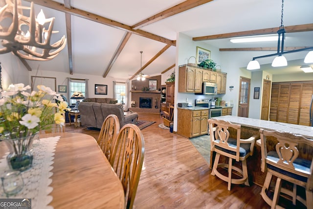 77 Chestatee Dr, Blairsville, GA 30512 - dining space featuring a ceiling fan, a fireplace, beamed ceiling, light wood finished floors, and high vaulted ceiling