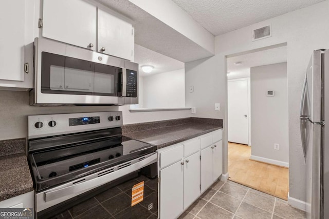 1504 Wingate Way, Atlanta, GA 30350 - kitchen featuring appliances with stainless steel finishes, dark countertops, white cabinets, a textured ceiling, and light tile patterned floors