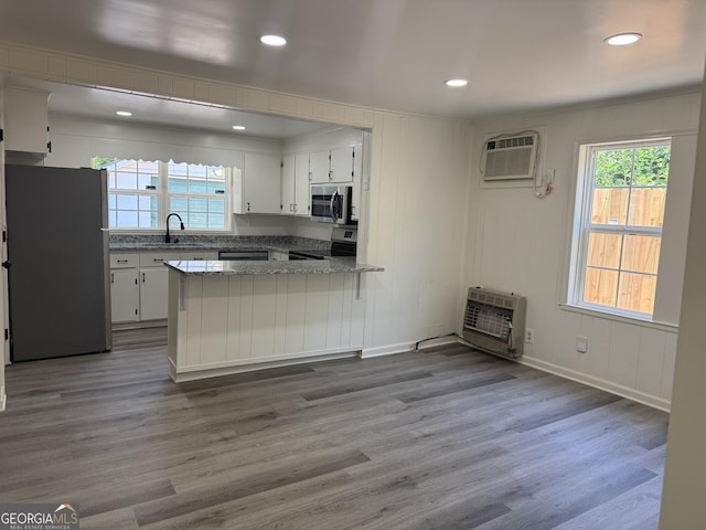 1220 Harmony St, Gainesville, GA 30501 - kitchen featuring appliances with stainless steel finishes, heating unit, a wall mounted AC, a peninsula, and white cabinets