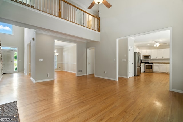 2832 Windrush Dr, Buford, GA 30518 - unfurnished living room with ceiling fan, a towering ceiling, light wood-style floors, and crown molding