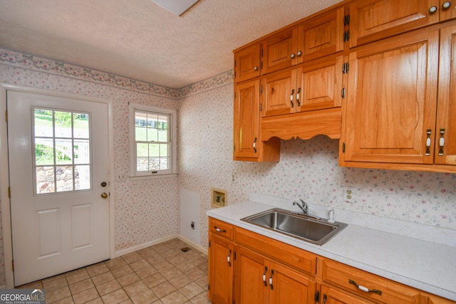 2722 Hidden Valley Rd, Hiawassee, GA 30546 - kitchen featuring light countertops, light tile patterned flooring, brown cabinetry, a textured ceiling, and wallpapered walls