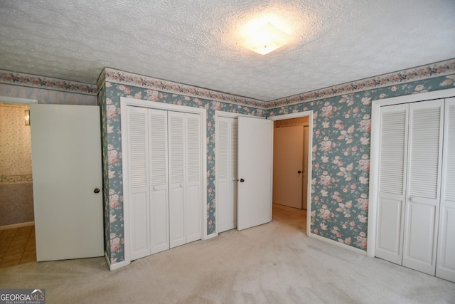 2722 Hidden Valley Rd, Hiawassee, GA 30546 - unfurnished bedroom with wallpapered walls, two closets, a textured ceiling, and carpet flooring