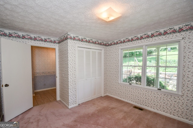 2722 Hidden Valley Rd, Hiawassee, GA 30546 - unfurnished bedroom with wallpapered walls, a textured ceiling, carpet flooring, and a closet