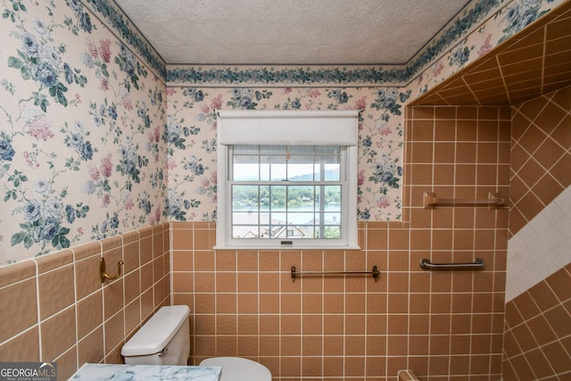 2722 Hidden Valley Rd, Hiawassee, GA 30546 - bathroom featuring wallpapered walls, a wainscoted wall, a textured ceiling, and tile walls