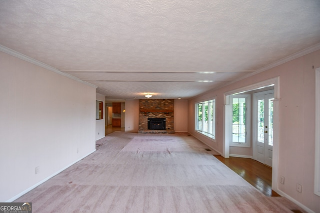 2722 Hidden Valley Rd, Hiawassee, GA 30546 - unfurnished living room with a textured ceiling, a fireplace, ornamental molding, light colored carpet, and light wood-style floors