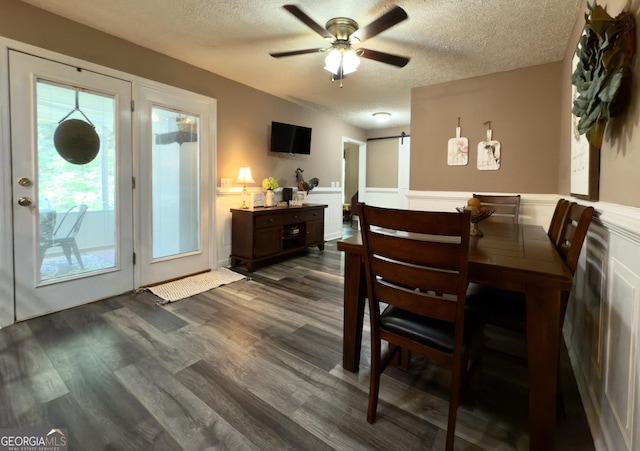 1780 Double Bridge Rd, Demorest, GA 30535 - dining area featuring a barn door, a textured ceiling, wainscoting, ceiling fan, and dark wood-style flooring