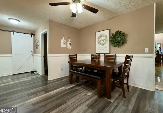 1780 Double Bridge Rd, Demorest, GA 30535 - dining area featuring a textured ceiling, a barn door, a ceiling fan, a wainscoted wall, and dark wood finished floors