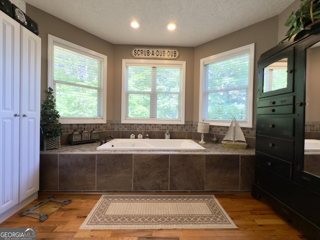 1780 Double Bridge Rd, Demorest, GA 30535 - bathroom featuring a garden tub, a textured ceiling, wood finished floors, and recessed lighting