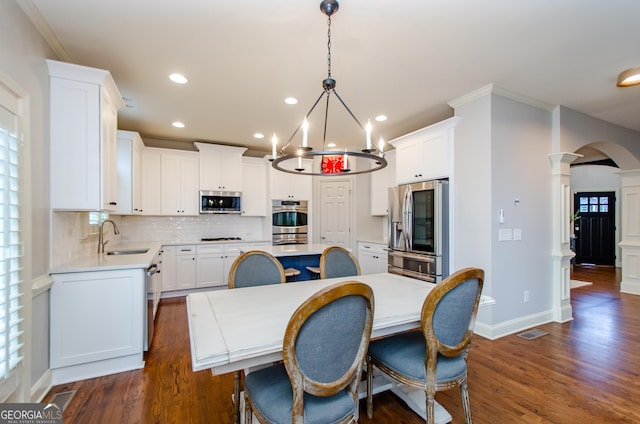 4645 Wykeshire Ct, Cumming, GA 30041 - dining room with ornate columns, dark wood finished floors, recessed lighting, a chandelier, and arched walkways