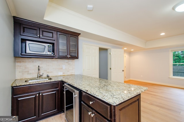 4645 Wykeshire Ct, Cumming, GA 30041 - kitchen featuring wine cooler, a raised ceiling, light wood finished floors, backsplash, and crown molding