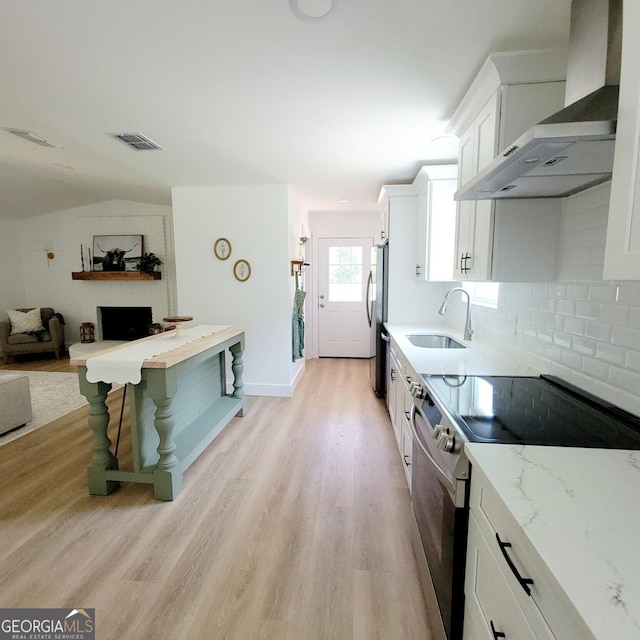 4749 Ga Highway 65, Pelham, GA 31779 - kitchen with stainless steel appliances, wall chimney exhaust hood, light wood finished floors, white cabinetry, and tasteful backsplash