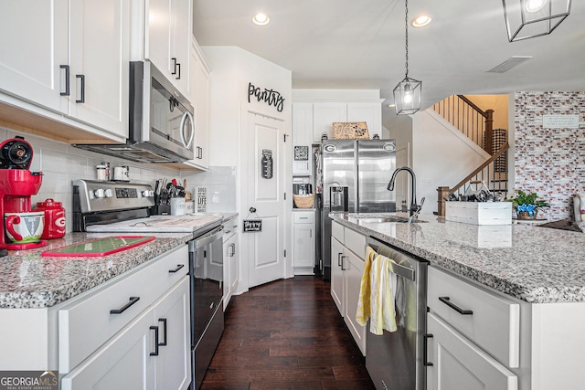 211 N Auburn Landing Pl, Auburn, GA 30011 - kitchen with appliances with stainless steel finishes, decorative backsplash, dark wood finished floors, white cabinetry, and decorative light fixtures