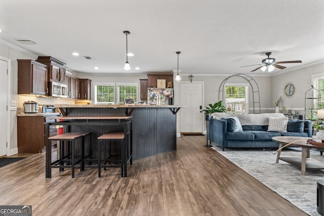 41 Bob White Ln, Newnan, GA 30263 - kitchen with stainless steel microwave, wood finished floors, a kitchen breakfast bar, ornamental molding, and a ceiling fan