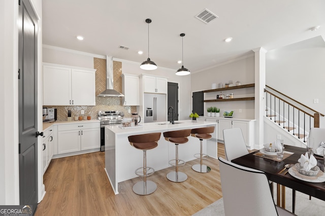 945 Willingham Dr Unit 3, Hapeville, GA 30354 - kitchen featuring stainless steel appliances, wall chimney range hood, light wood finished floors, ornamental molding, and a breakfast bar area
