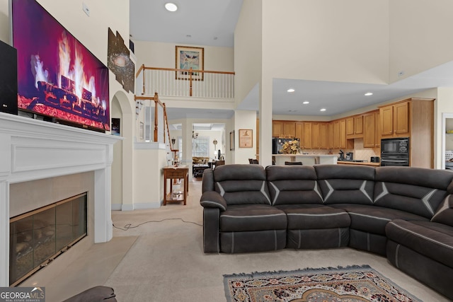 7769 Copper Kettle Way, Flowery Branch, GA 30542 - living room with a towering ceiling, light colored carpet, a tiled fireplace, and recessed lighting