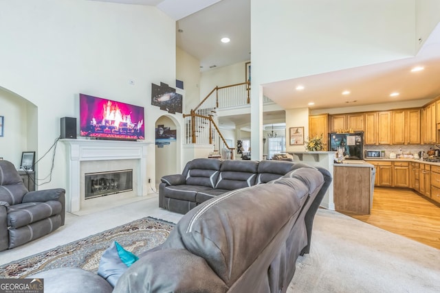 7769 Copper Kettle Way, Flowery Branch, GA 30542 - living area with high vaulted ceiling, stairs, a high end fireplace, recessed lighting, and arched walkways