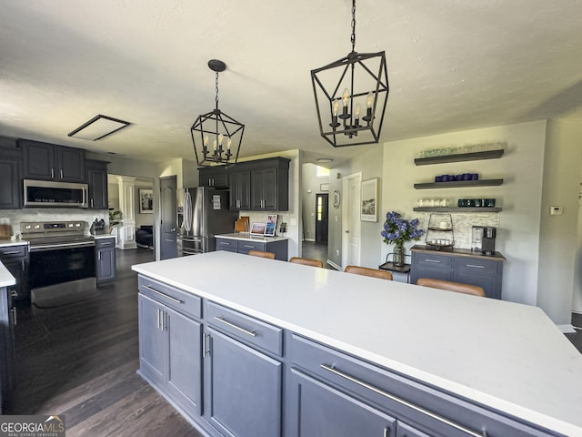 184 Fashion Xing, Mcdonough, GA 30252 - kitchen with stainless steel appliances, a chandelier, light countertops, dark wood-style flooring, and hanging light fixtures