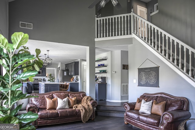 184 Fashion Xing, Mcdonough, GA 30252 - living area featuring dark wood-type flooring, a ceiling fan, a high ceiling, stairs, and a chandelier