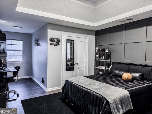 184 Fashion Xing, Mcdonough, GA 30252 - bedroom with dark wood-style flooring, an office area, a raised ceiling, and a decorative wall