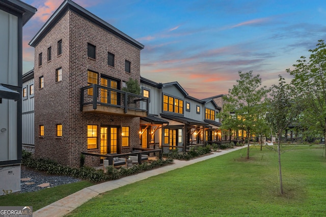 937 Willingham Dr Unit 7, Hapeville, GA 30354 - back of house at dusk with a balcony, brick siding, a lawn, and board and batten siding