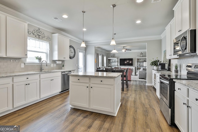 17 October Ave, Newnan, GA 30265 - kitchen featuring appliances with stainless steel finishes, a kitchen island, white cabinetry, ornamental molding, and recessed lighting