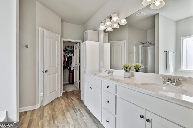 17 October Ave, Newnan, GA 30265 - bathroom with a stall shower, double vanity, wood finished floors, a walk in closet, and a chandelier