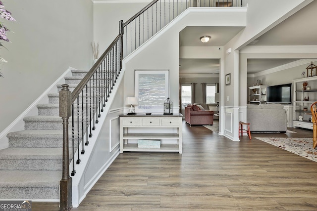 17 October Ave, Newnan, GA 30265 - staircase with a towering ceiling, ornamental molding, wood finished floors, wainscoting, and a decorative wall
