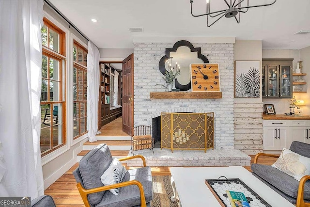 106 Draughons Dr, Saint Simons, GA 31522 - living room featuring a chandelier, wood finished floors, and a brick fireplace