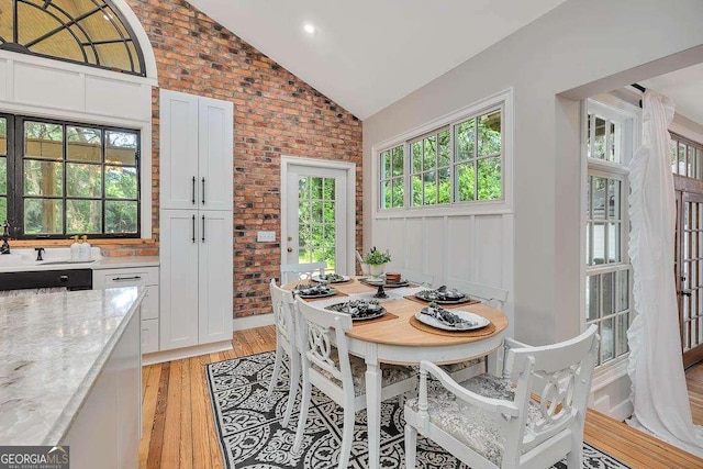 106 Draughons Dr, Saint Simons, GA 31522 - dining space featuring vaulted ceiling, light wood finished floors, and brick wall