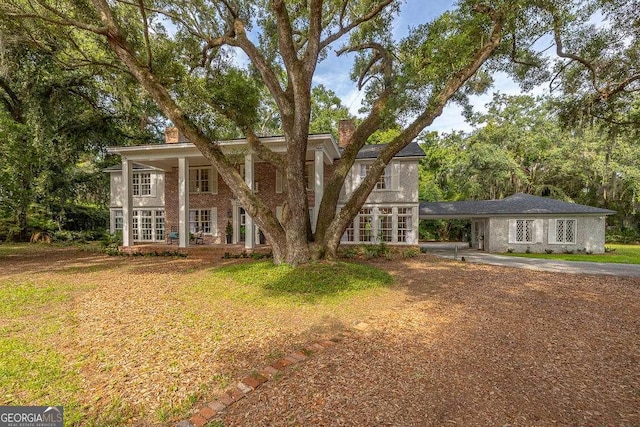 106 Draughons Dr, Saint Simons, GA 31522 - neoclassical / greek revival house featuring a chimney, driveway, an attached carport, french doors, and brick siding