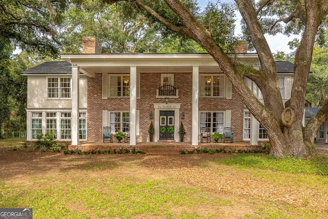 106 Draughons Dr, Saint Simons, GA 31522 - neoclassical / greek revival house with a chimney, a porch, brick siding, and a front yard