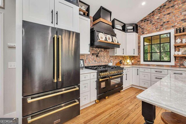 106 Draughons Dr, Saint Simons, GA 31522 - kitchen with high quality appliances, custom range hood, open shelves, light wood-type flooring, and white cabinetry