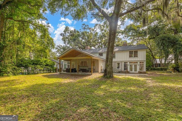 106 Draughons Dr, Saint Simons, GA 31522 - rear view of house with french doors, a chimney, a lawn, and a patio area
