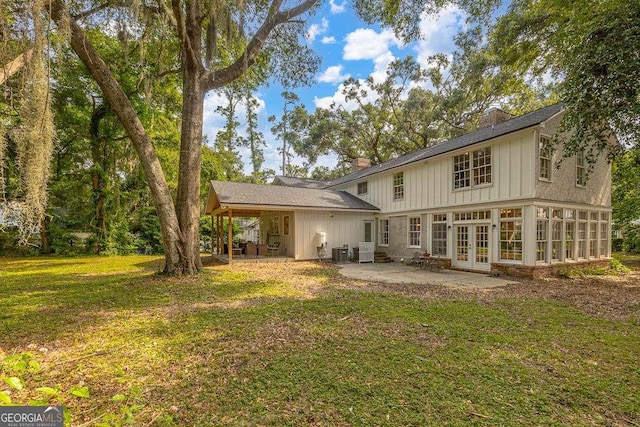 106 Draughons Dr, Saint Simons, GA 31522 - back of house with french doors, board and batten siding, a patio, a yard, and a chimney