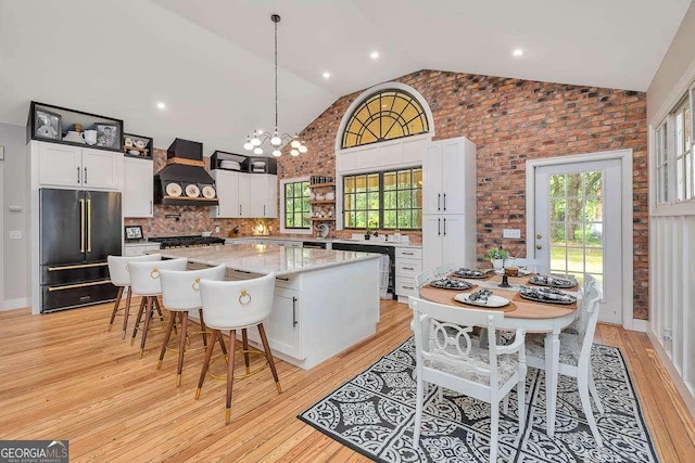 106 Draughons Dr, Saint Simons, GA 31522 - kitchen with high end fridge, premium range hood, white cabinetry, a kitchen island, and light wood finished floors