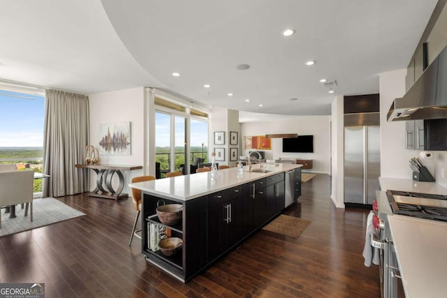 3325 Piedmont Rd NE Unit 2006, Atlanta, GA 30305 - kitchen with appliances with stainless steel finishes, dark cabinetry, open shelves, light countertops, and wall chimney exhaust hood