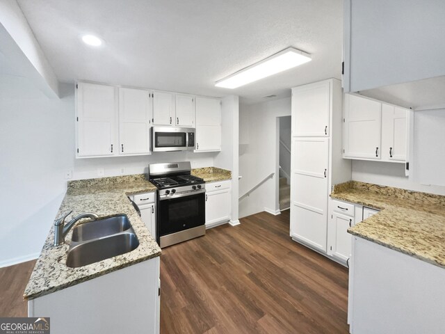 5021 Rodrick Trce, Marietta, GA 30066 - kitchen featuring stainless steel appliances, light stone countertops, dark wood-style floors, a peninsula, and white cabinetry
