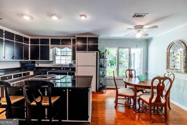 205 Castlegate Rd, Macon, GA 31210 - kitchen with freestanding refrigerator, dark countertops, wood finished floors, ceiling fan, and dark cabinets