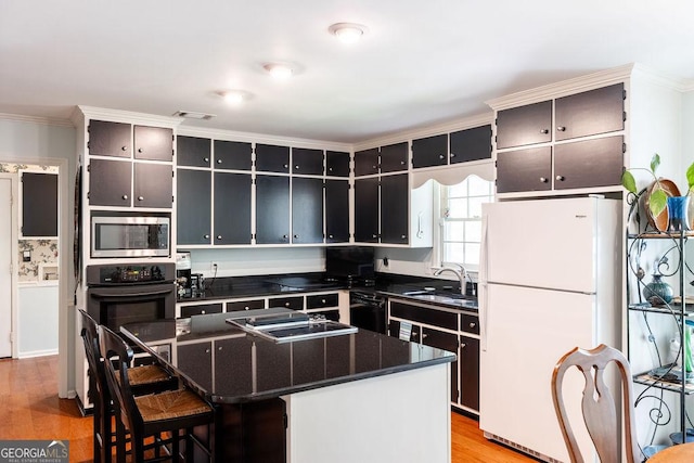 205 Castlegate Rd, Macon, GA 31210 - kitchen featuring black appliances, dark countertops, light wood-type flooring, a center island, and ornamental molding