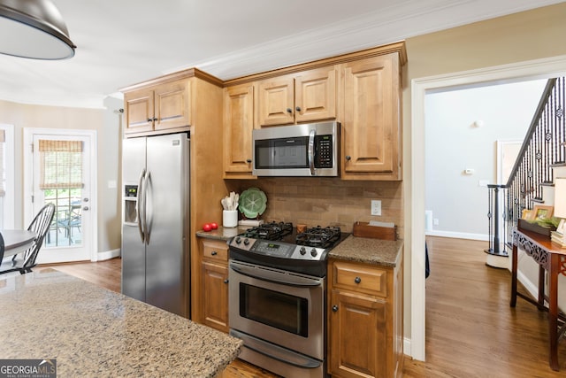 1030 Spring Lake Dr, Bishop, GA 30621 - kitchen featuring appliances with stainless steel finishes, crown molding, decorative backsplash, wood finished floors, and light stone countertops