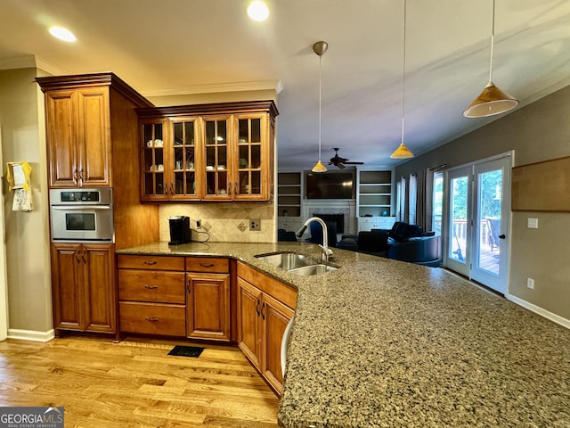 703 Overlook Pt, Woodstock, GA 30189 - kitchen with oven, a fireplace, brown cabinetry, glass insert cabinets, and stone counters